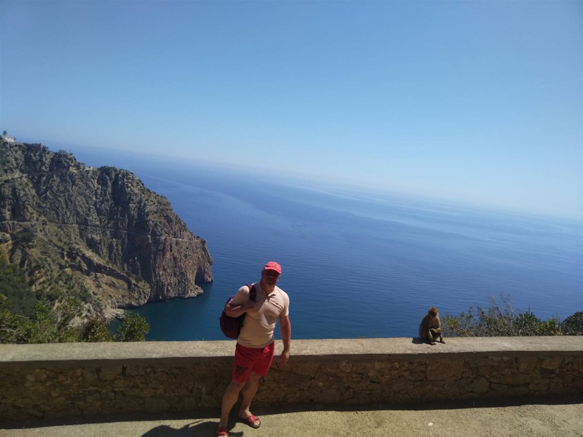 Rubes Levada on the coast road above the sea near Béjaïa, with a Barbary macaque sitting on the wall